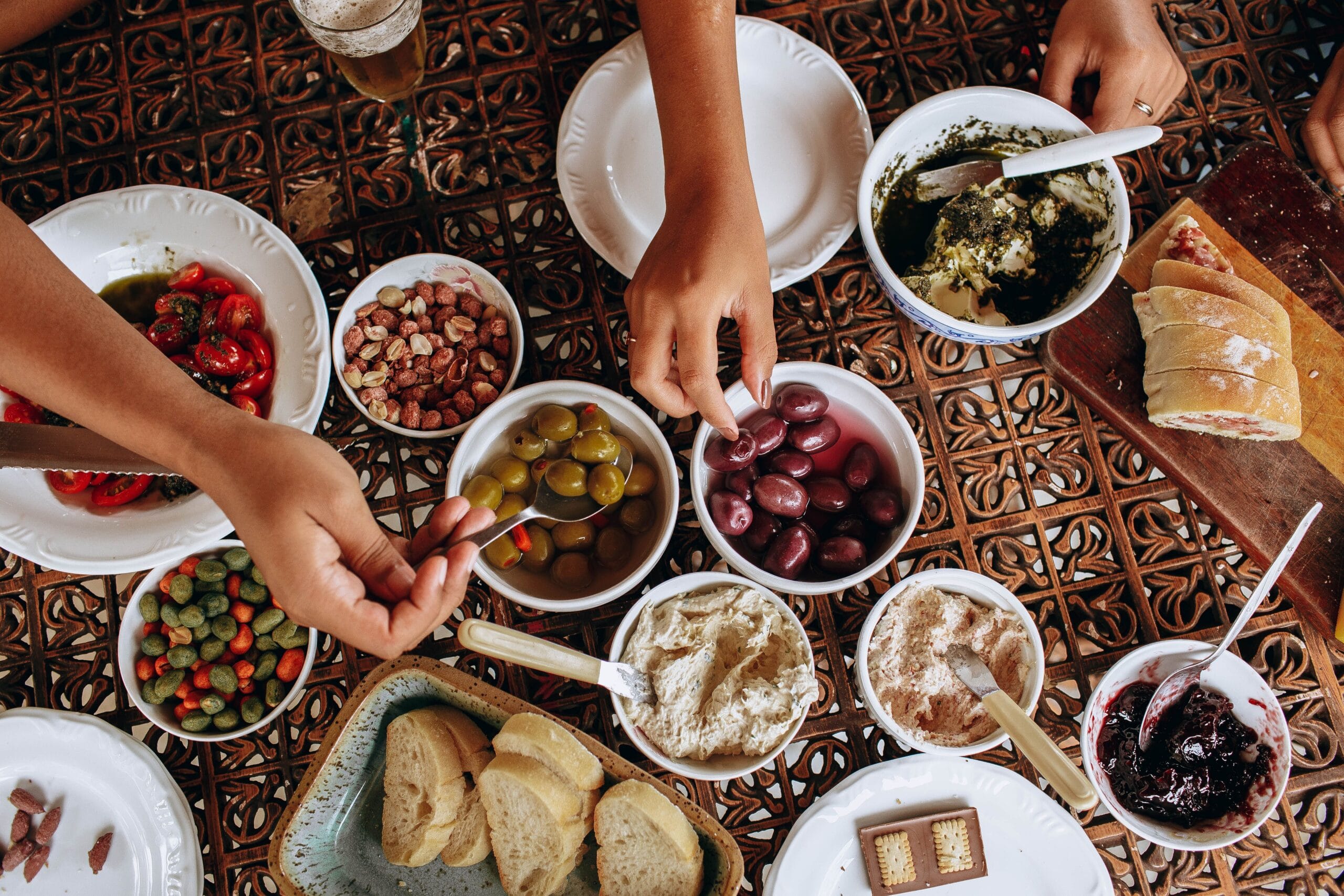 An overhead view of a shared table laid with olives, breads, dips and local dishes