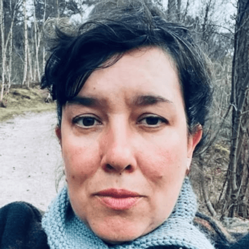 Maaike van Geijn, Dutch knitwear designer, on a woodland path in a hand-knitted scarf