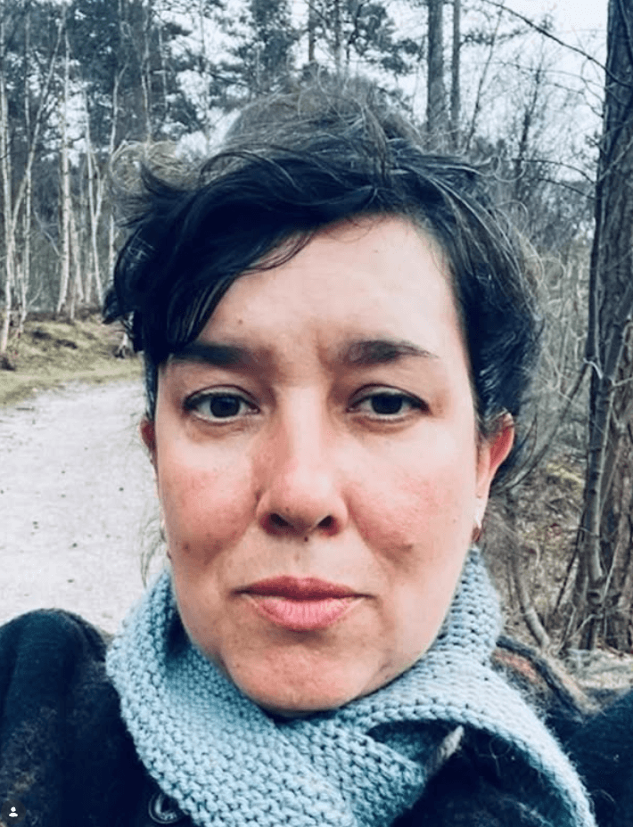 Maaike van Geijn, Dutch knitwear designer, on a woodland path in a hand-knitted scarf