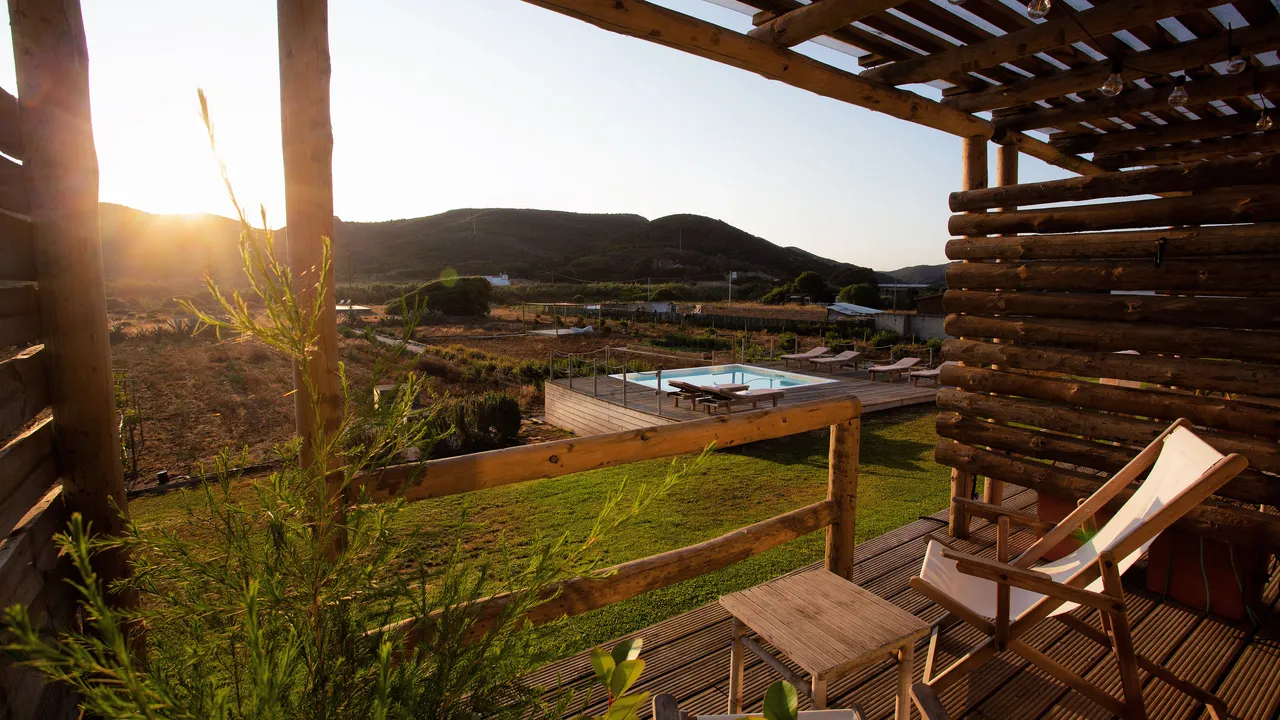 A timber terrace looking past a pool to open hills at golden hour