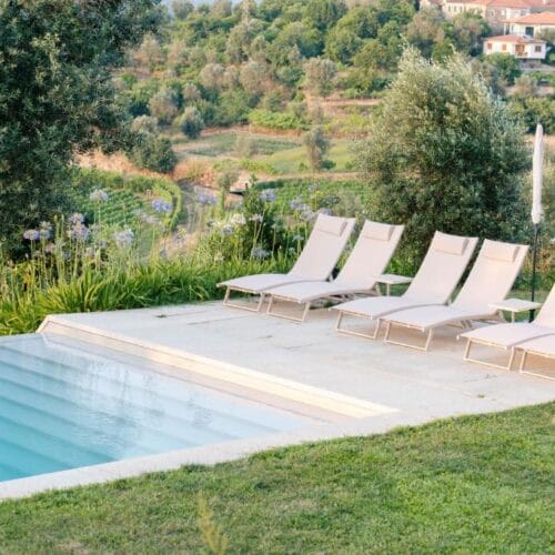 The pool at Casa da Granja with white loungers, looking out over the terraced vineyards of the Douro
