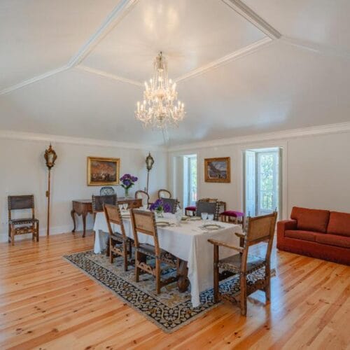 The dining room at Casa da Granja, with a long table, chandelier and wooden floor