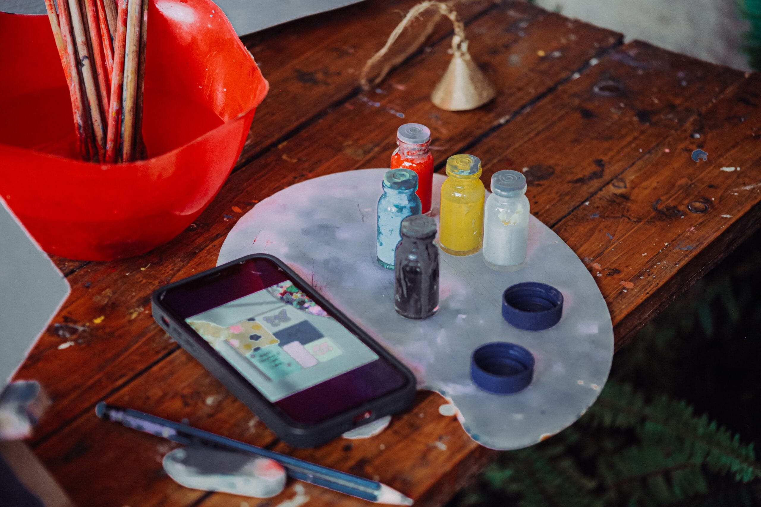 A phone showing a moodboard of colours and textures on a paint-splattered worktable