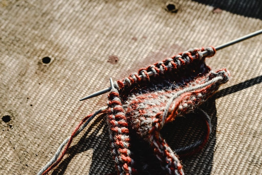 Close-up of rust and cream knitting on a metal needle