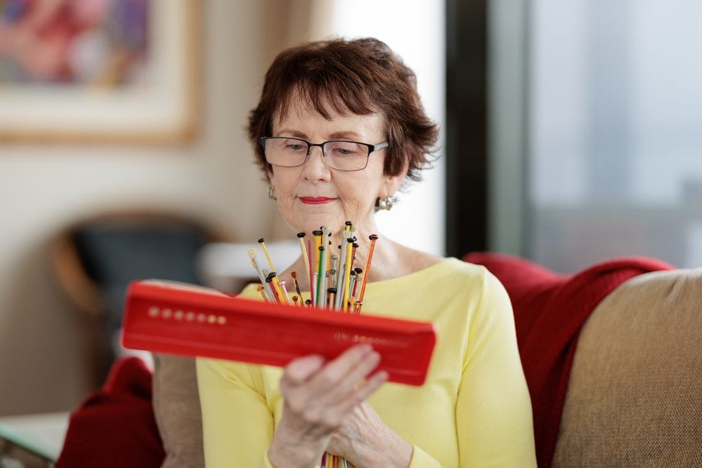 Knitter checking needle sizes with a gauge before a colorwork class