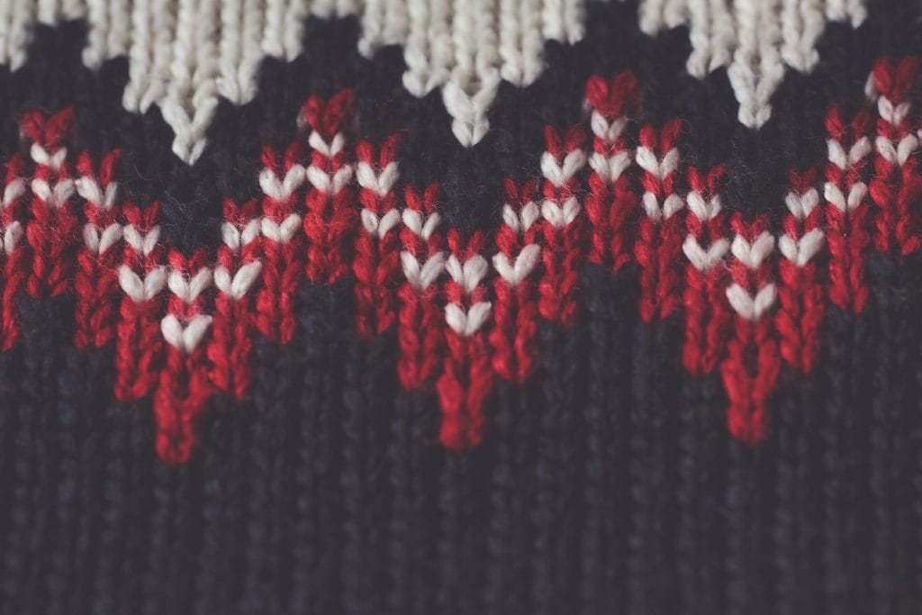 Black knitted fabric with a red and white stranded zigzag border