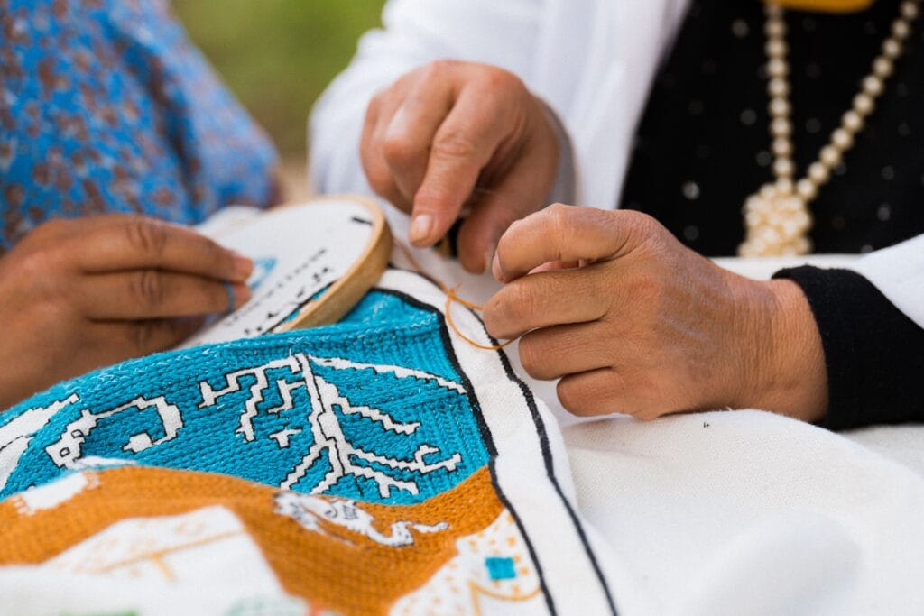 Hands working a detailed traditional embroidery pattern